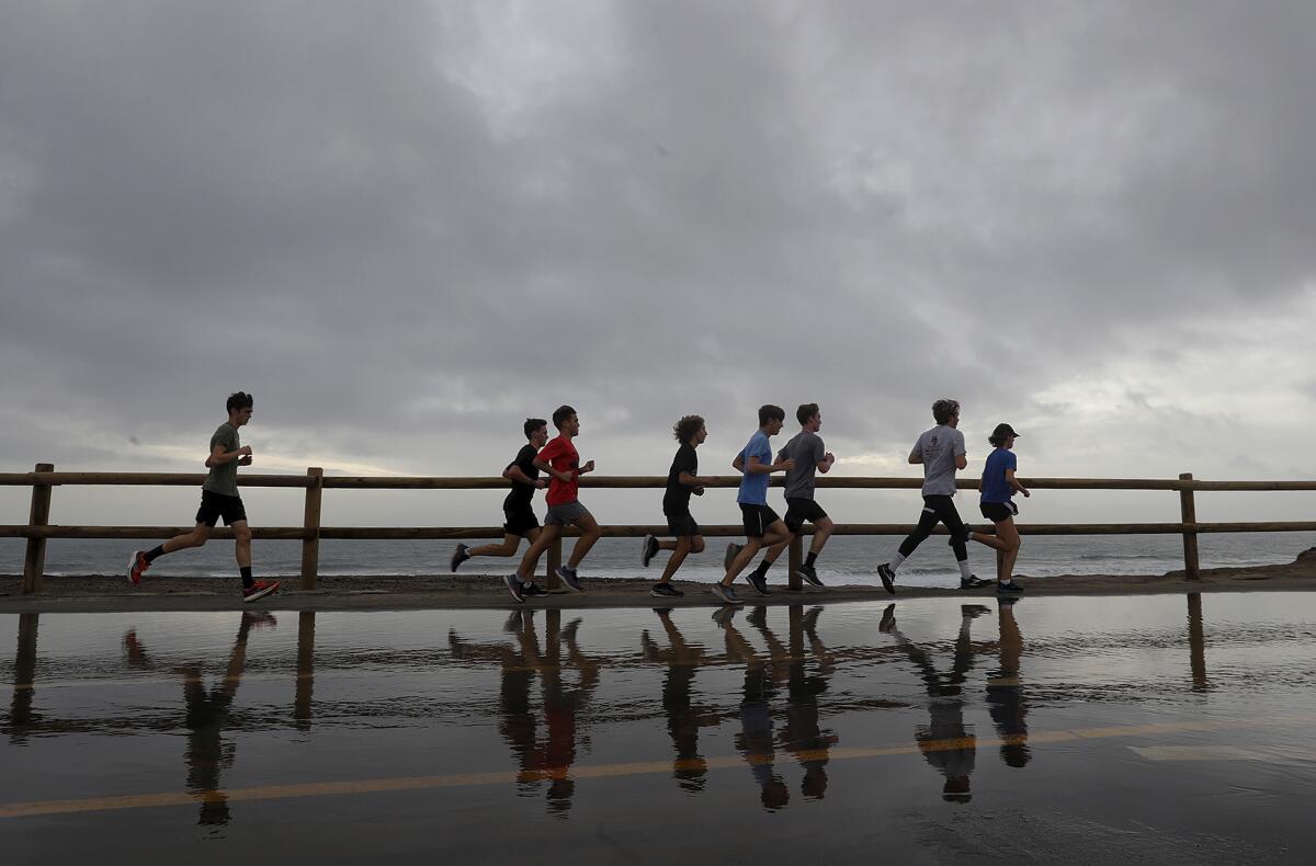 A group of runners pace up the the bike path over a puddle near Goldenwest Street and Coast Highway.