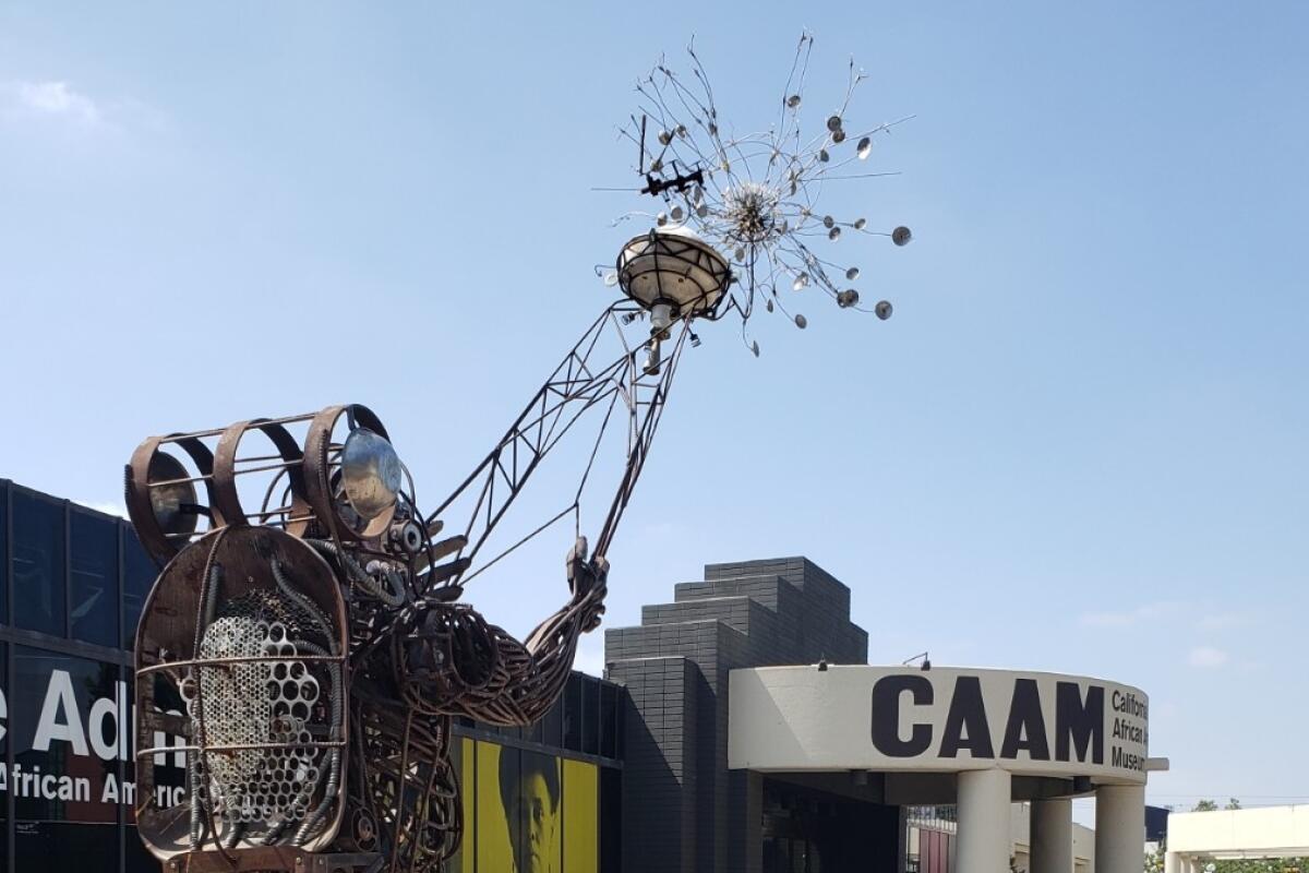 A outdoor rebar sculpture of a person pointing a divining rod toward a starburst.