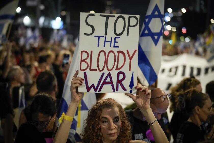 Una manifestante sostiene un cartel durante una protesta que marca nueve meses desde el inicio de la guerra y pide la liberación de los rehenes retenidos en la Franja de Gaza por el grupo armado Hamás, en Tel Aviv, Israel, el domingo 7 de julio de 2024. El cartel dice "detengan la maldita guerra". (AP Foto/Leo Correa)