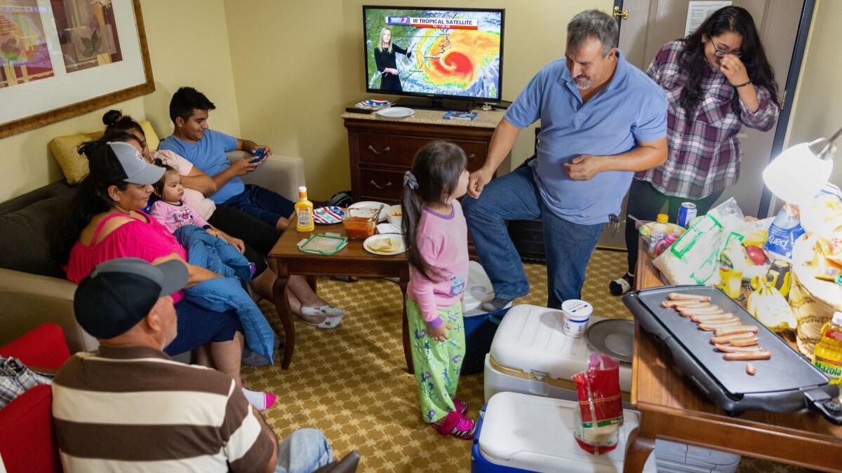The Ramos family prepares dinner and watches the weather forecast as they wait out Hurricane Florence at the Country Inn & Suites in Wilmington, N.C.