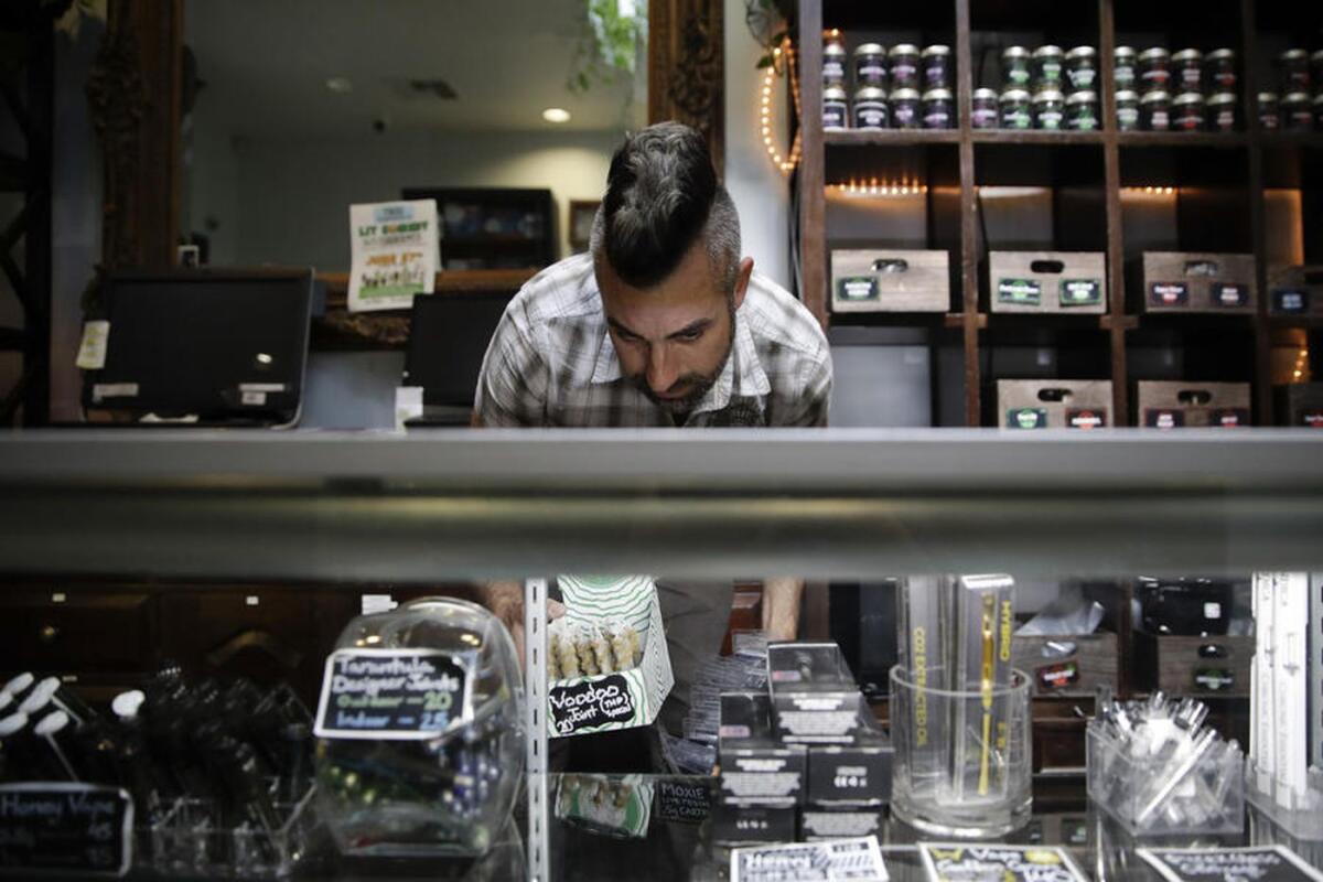 Jerred Kiloh, owner of the Higher Path medical marijuana dispensary, stocks shelves with cannabis products in Los Angeles.