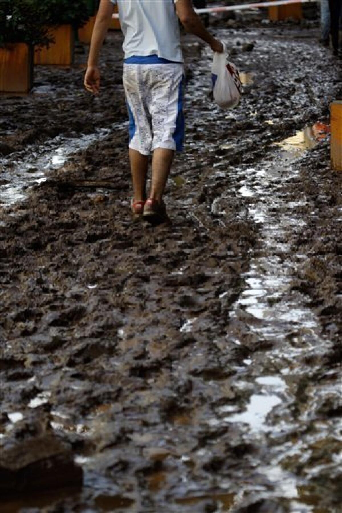 A young man walks down a street filled with mud Sunday, Feb. 21 2010, in Funchal, the Madeira Island's capital. Rocks and mud were brought down from the hills to the streets of Funchal by flash floods on Saturday and the local government has confirmed some dead. (AP Photo/Armando Franca)