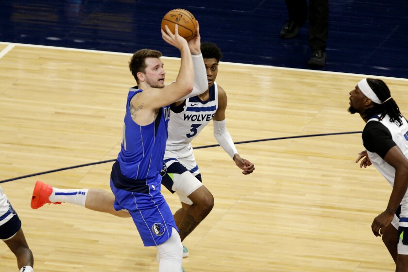 Dallas Mavericks guard Luka Doncic (77) passes in front of Minnesota Timberwolves forward Jaden McDaniels (3) and center Naz Reid (11) in the second quarter during an NBA basketball game, Sunday, May 16, 2021, in Minneapolis. (AP Photo/Andy Clayton-King)