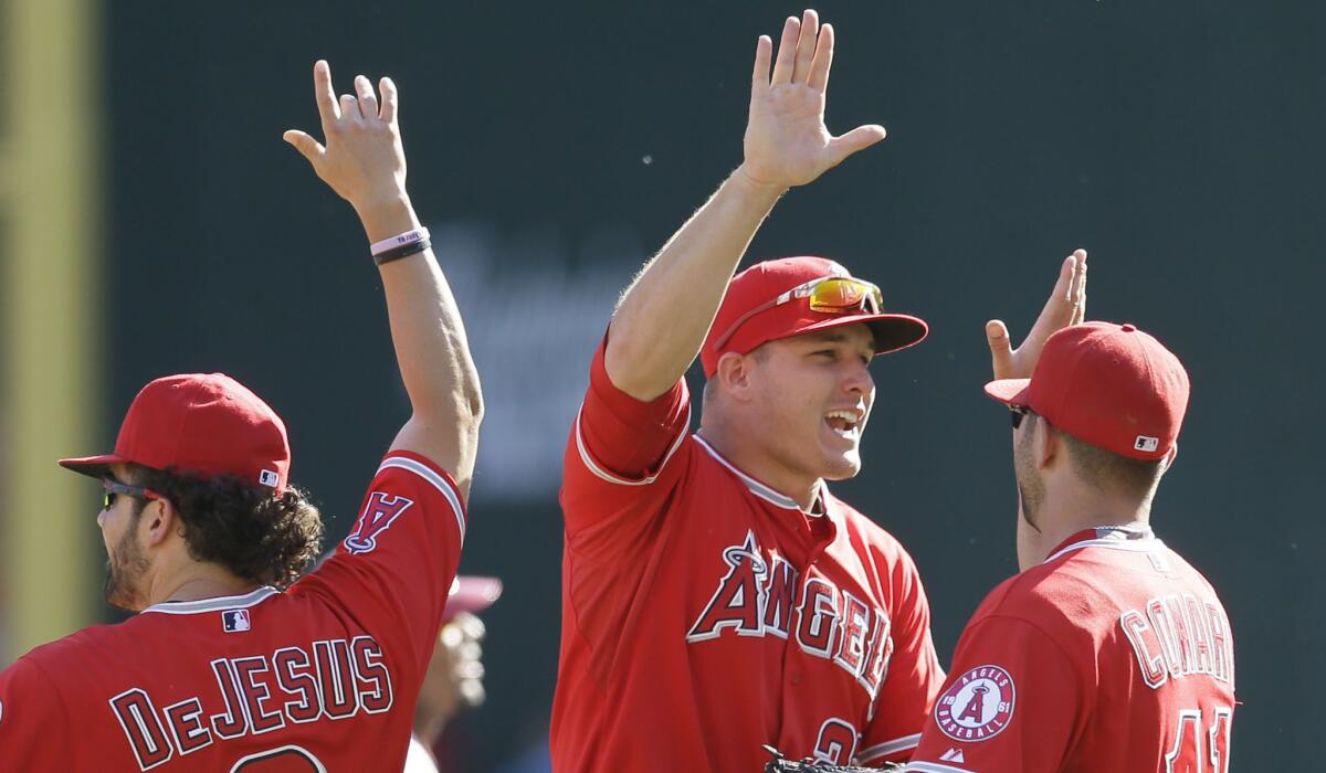 Angels' Mike Trout, center, celebrates with teammates David DeJesus, left, and Kaleb Cowart after an 11-10 win over Texas on Saturday.