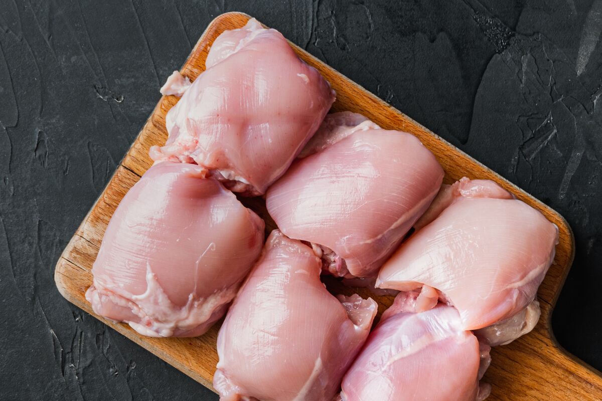 Boneless, skinless chicken thighs on a cutting board.
