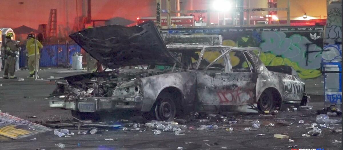 A burned-out car sits in a parking lot.