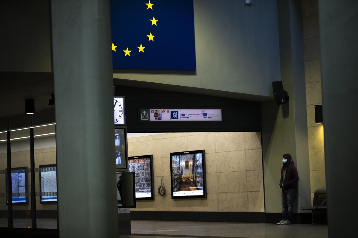 A man wearing a face mask waits for a train in Brussels