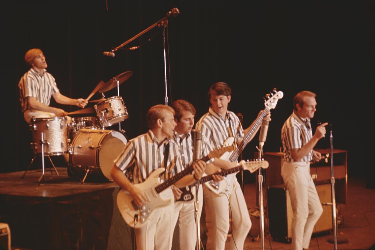 The Beach Boys performing in striped shirts and white pants.