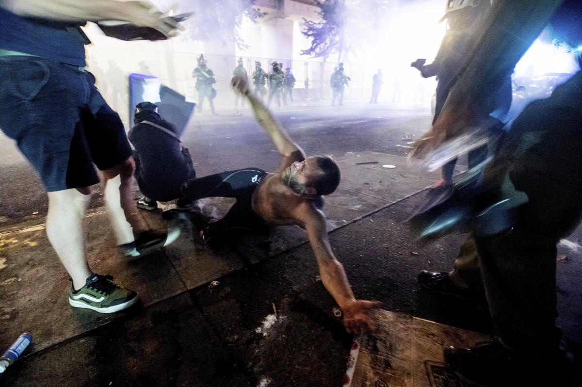 A protester lies on the ground as federal officers use chemical irritants to disperse demonstrators in Portland, Ore.