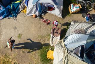 Los Angeles, CA - June 26: A homeless woman waits as Inside Safe workers canvas a homeless camp on 86th and Broadway to move people out of the encampment and into hotel and motel rooms Wednesday, June 26, 2024 in Los Angeles, CA. (Brian van der Brug / Los Angeles Times)