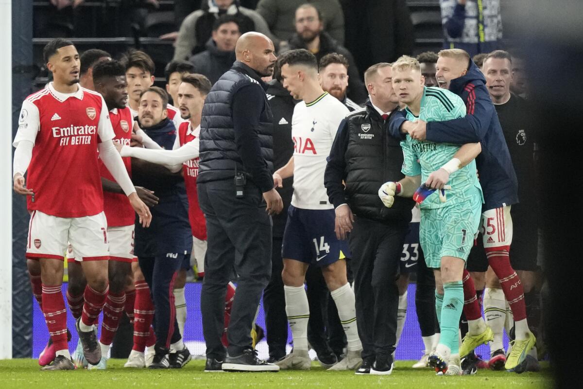Arsenal goalkeeper Aaron Ramsdale, in green, is ushered away after an incident at the end of the English Premier League soccer match between Tottenham Hotspur and Arsenal at the Tottenham Hotspur Stadium in London, England, Sunday, Jan. 15, 2023. The incident happened when a spectator climbed onto an advertising board and appeared to kick Ramsdale after the team's 2-0 win over Tottenham in the Premier League. (AP Photo/Frank Augstein)