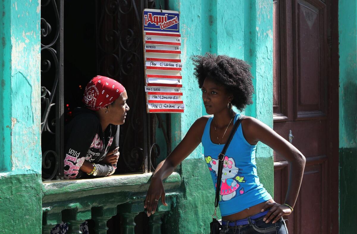 Two women chat at a window of a cafe in Havana, Cuba.