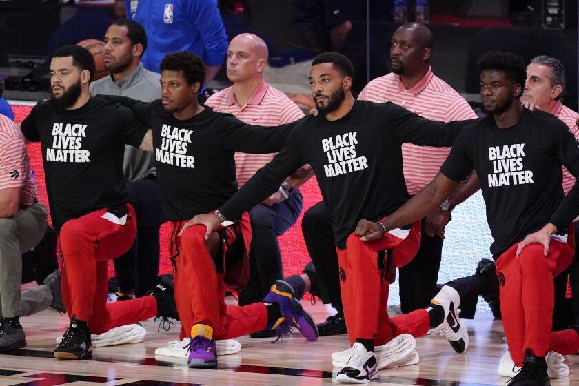 Members of the Toronto Raptors kneel on the court during the playing of the national anthem.