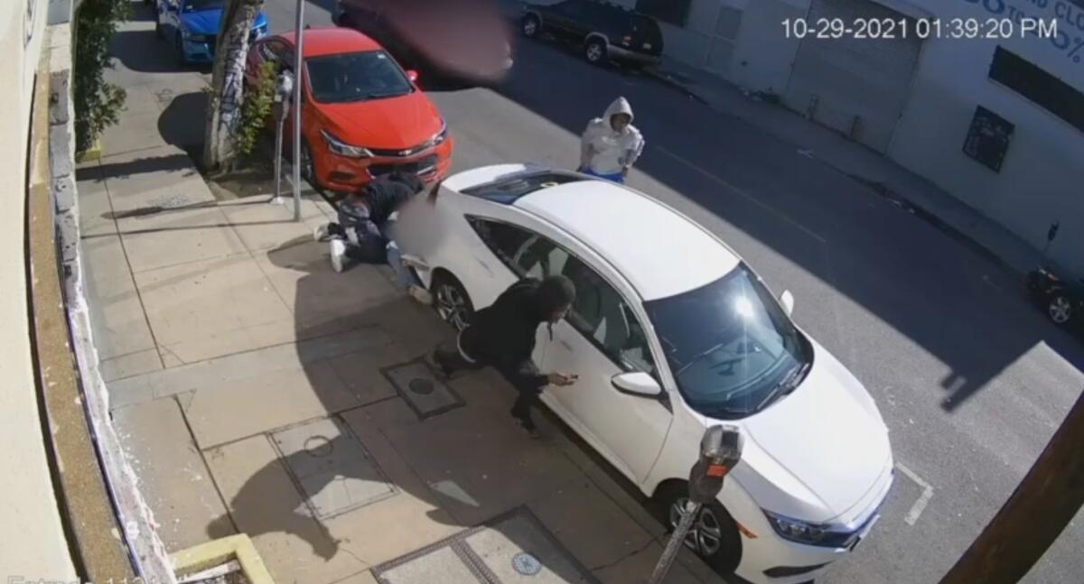An image from a surveillance camera shows three men standing near a parked car.