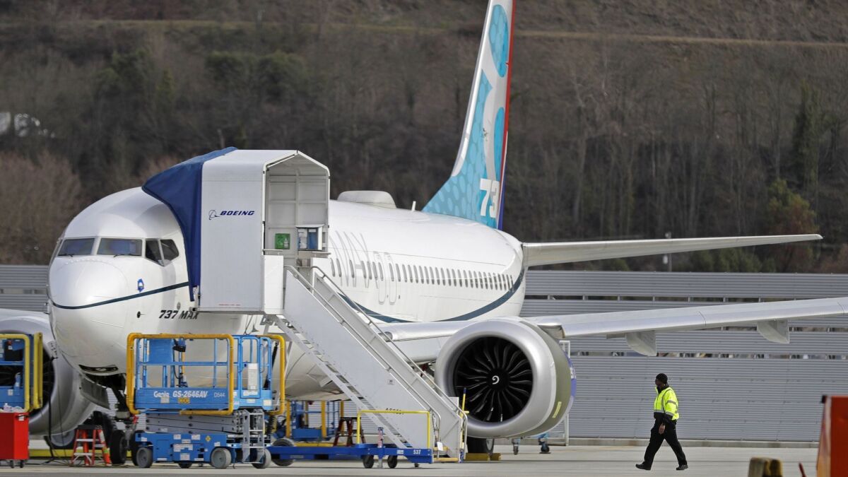 A worker walks next to a Boeing 737 Max 8 airplane parked at Boeing Field in Seattle.