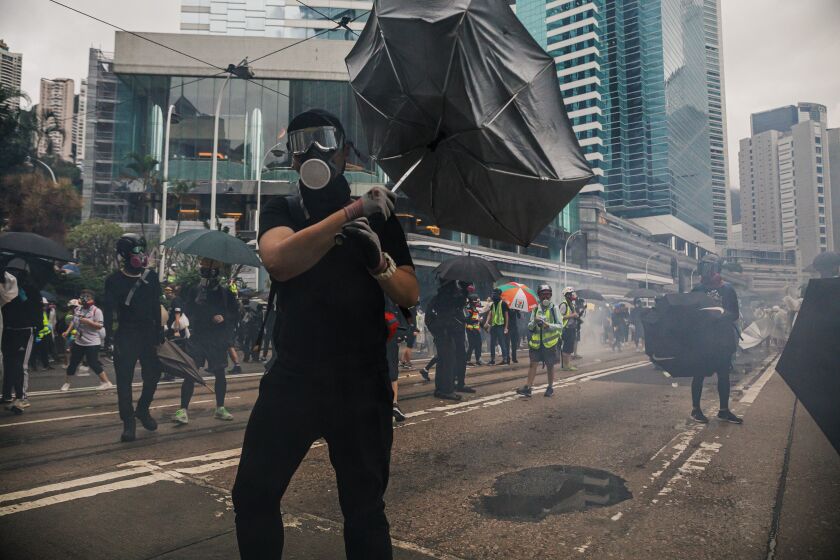 HONG KONG, CHINA -- SUNDAY, OCTOBER 6, 2019: Anti-government demonstrators try to contain tear gas canisters launched by the police as more than a hundred thousand people took to the streets to protest a mask ban aimed at quashing violence during four months of pro-democracy gatherings in Hong Kong, on Oct. 6, 2019. Despite Chief Executive Carrie Lam’s bowing to the demonstrators’ key demand – withdrawal of a controversial extradition bill, pro-democracy demonstrators are now calling for Lam to immediately meet the rest of their demands. This includes an independent inquiry into police’s use of force, amnesty for those arrested, a halt on the use of the word “Riot” when describing the rallies, and lastly, calls for universal suffrage for the people of Hong Kong. (Marcus Yam / Los Angeles Times)