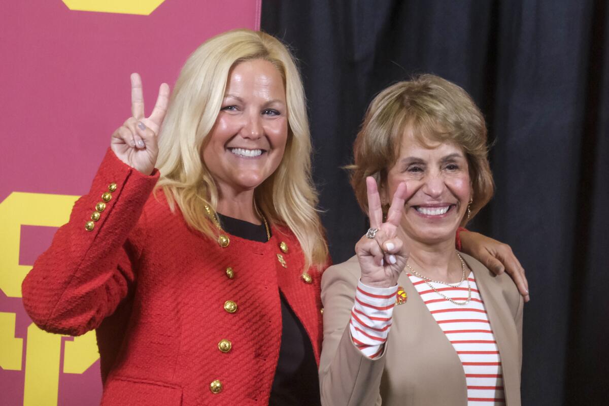 USC athletic director Jennifer Cohen, left, USC president Carol Folt show victory signs during a news conference.