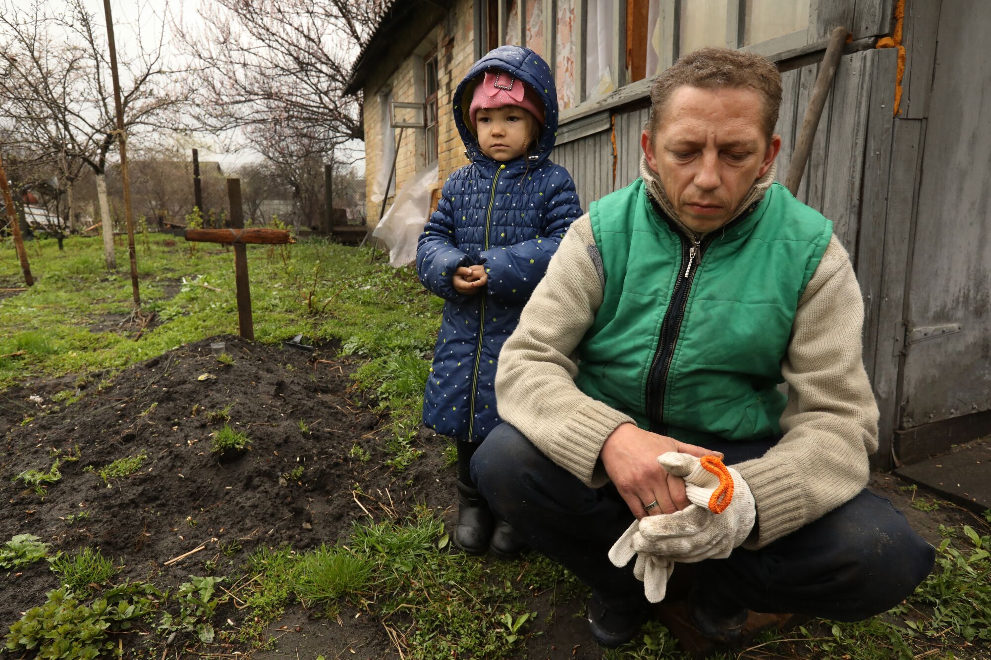 A year of war: Los Angeles Times photographers document the battle in Ukraine 18 A 4-year-old girl and her father next to a grave with a simple wooden cross