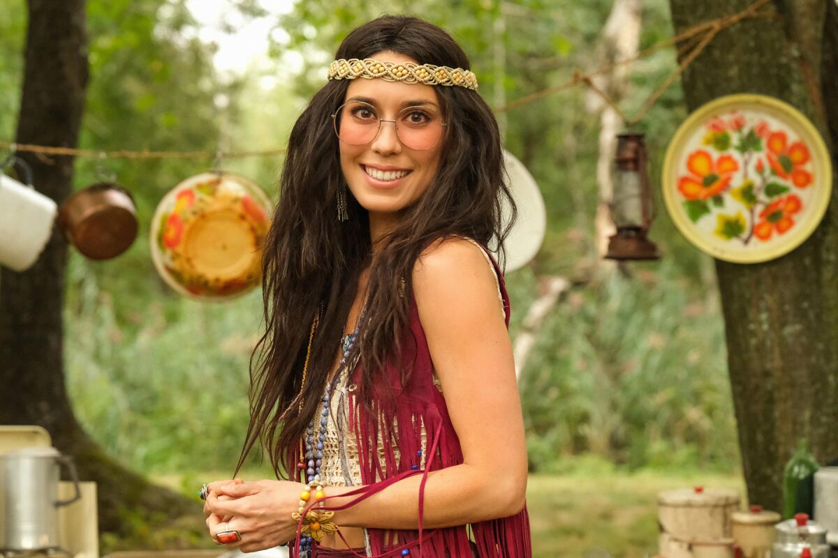 A woman dressed as a hippie in a forest.