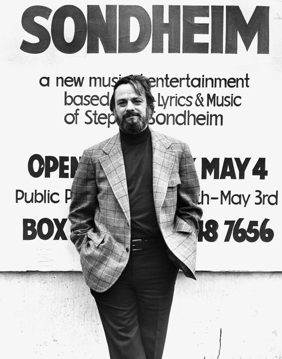 Stephen Sondheim stands in front of an advertisement for one of his shows.