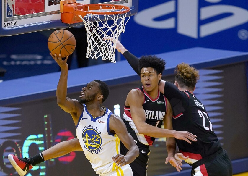 Golden State Warriors forward Andrew Wiggins (22) drives to the basket between Portland Trail Blazers guard Anfernee Simons (1) and center Jusuf Nurkic (27) during the first half of an NBA basketball game in San Francisco, Friday, Jan. 1, 2021. (AP Photo/Tony Avelar)