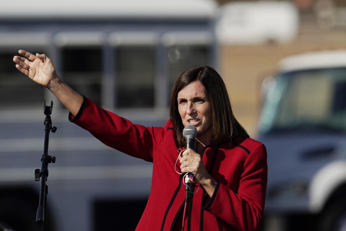 Sen. Martha McSally holds out an arm and holds a microphone with her other arm.