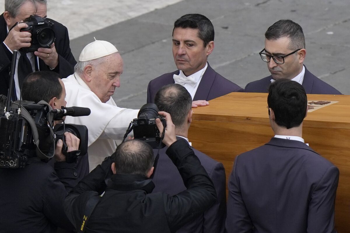 Pope Francis laying a hand on the coffin of Pope Emeritus Benedict XVI