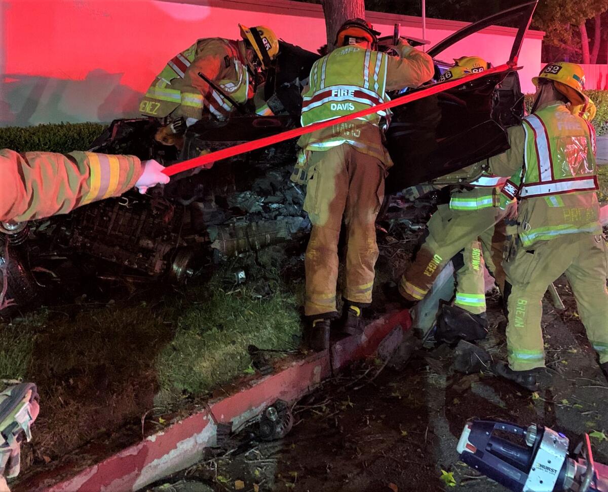 Firefighters use the jaws of life to rescue people from a collision on Costa Mesa's Baker Street.