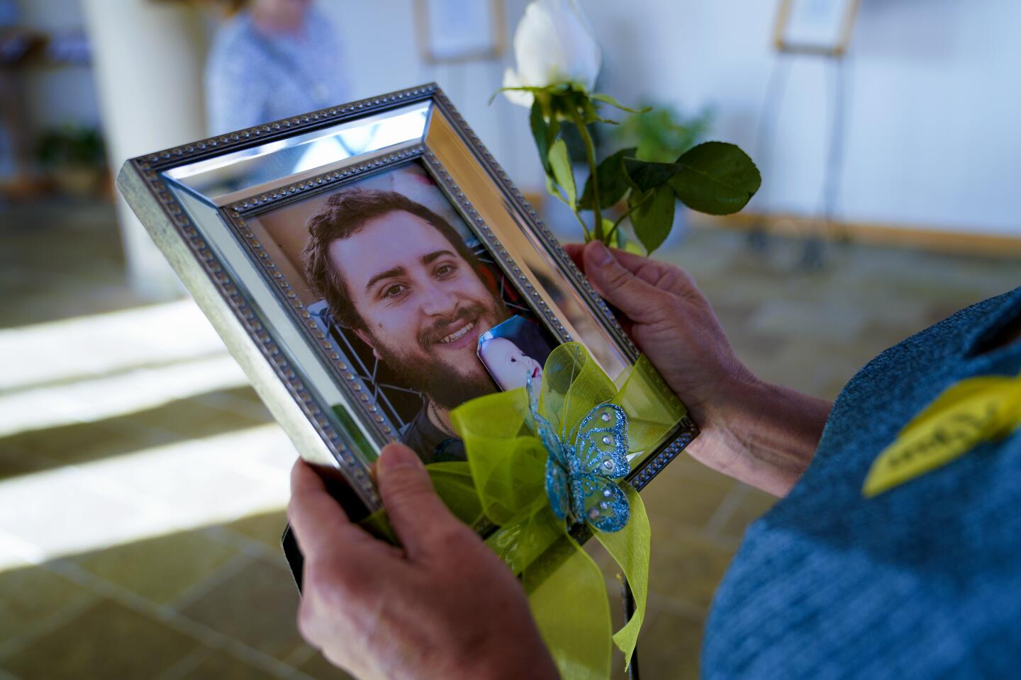 Cecilia Bradley carried a photo of her son, Ryan into the nave before the start of Mass for Survivors of Suicide Loss held at Our Mother of Confidence.