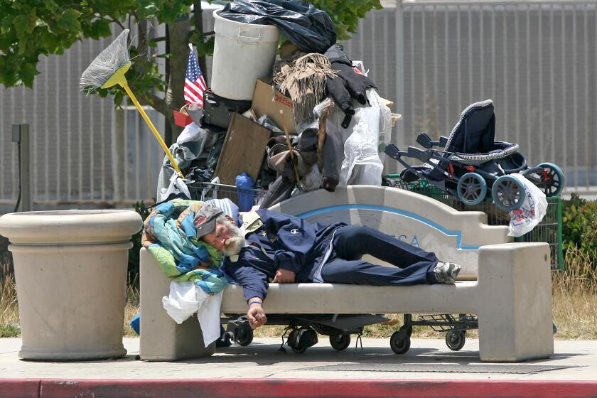 A known homeless man sleeps on a city bench on Harbor Blvd in Costa Mesa. Orange County applied for funding from Project Roomkey, which secures 15,000 hotel and motel rooms to provide short-term shelter for vulnerable homeless people during the COVID-19 pandemic.