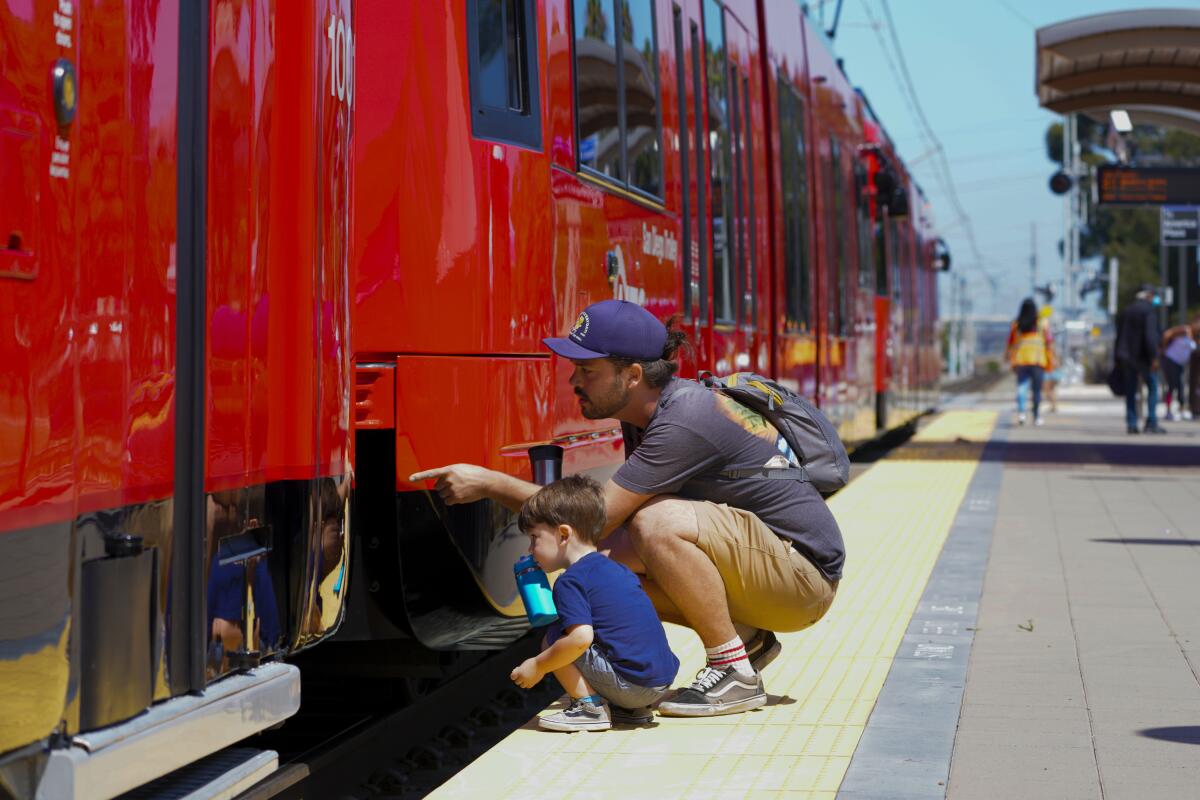 A man and his son squat and inspect Trolley cars