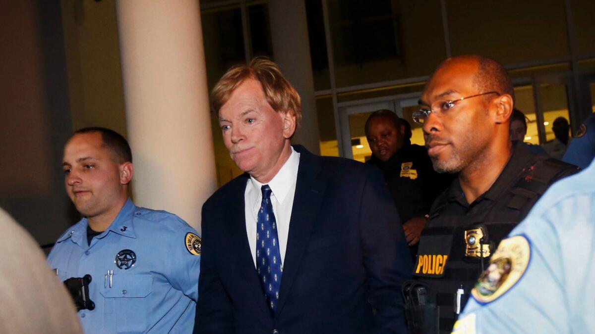 Former Klansman and current U.S. Senate candidate David Duke is hastily escorted to a police car after a debate at Dillard University in New Orleans on Wednesday.