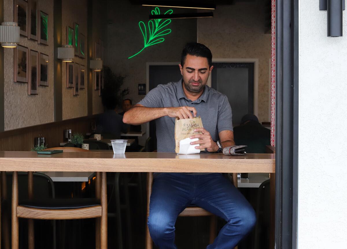 Kamyar Dibaj enjoys his lunch sitting in the open window dinning area at Sababa Falafel Shop.