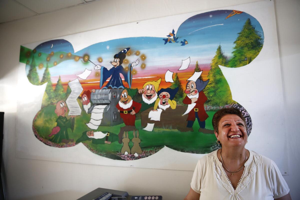 Extra Copy owner Marine Ter-Pogosyan stands in front of the store's Disney mural, which was painted by a customer. The Los Feliz building where her business is located once housed the first office of Disney Bros. Studio.