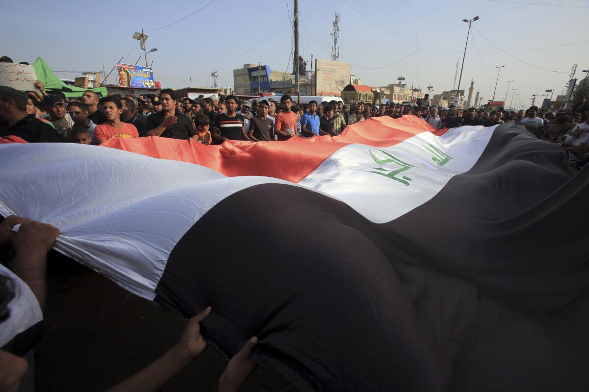 Protesters in Sadr City hold national flags as they rally on May 12 against security forces that have failed to protect them from car bombs.