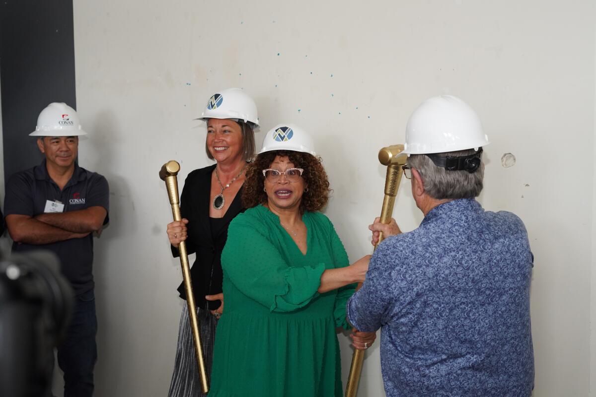 Dea Hurston, center, in green, takes a sledgehammer for the "wall-breaking" ceremony in Carlsbad.