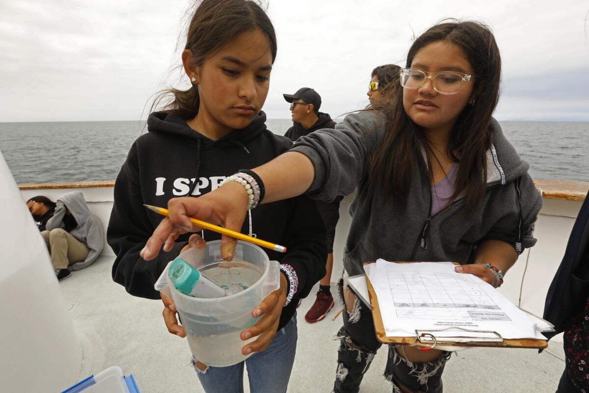 Alejandra Jimenez and Jalen Telles take pH and temperature water samples.
