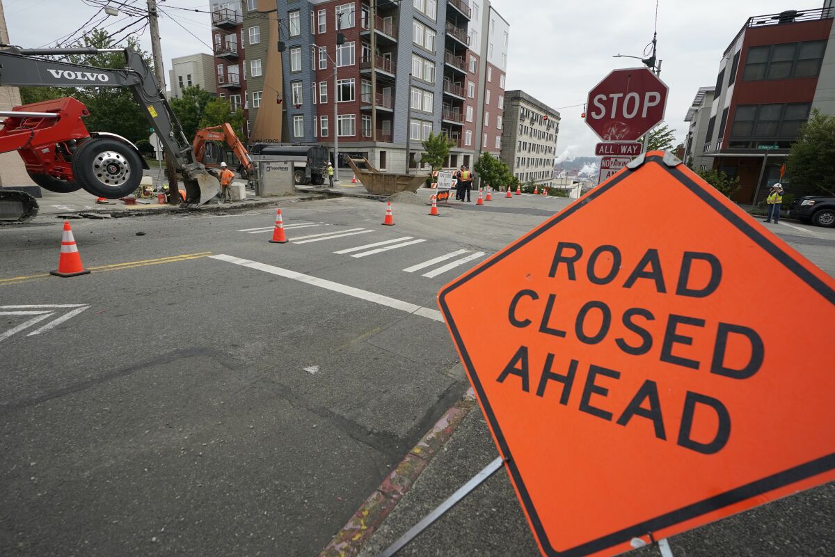 A sign is shown near ongoing work on a project to replace water main pipes in downtown Tacoma, Wash.