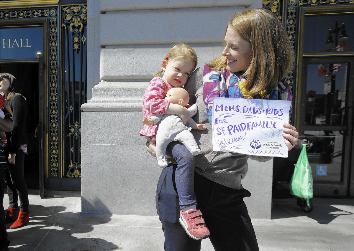 Kim Turner holds her daughter, Adelaide Turner Winn, before a rally supporting paid family leave at San Francisco City Hall. San Francisco is made labor history this month by becoming the first U.S. city to require employers to offer fully paid leave to new parents.