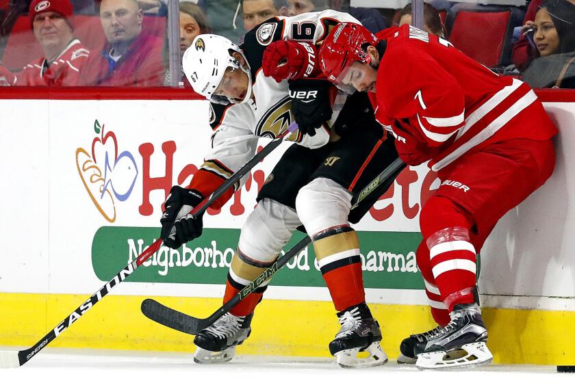 Ducks center Rickard Rakell and Hurricanes defenseman Ryan Murphy (7) battle for the puck along the boards during their game Thursday night.