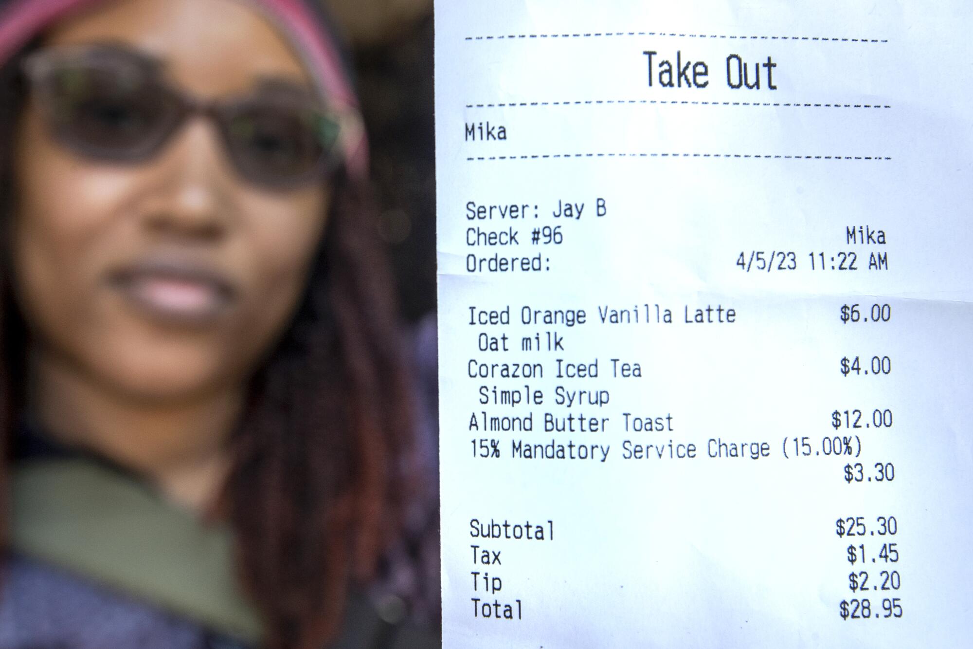 A woman in sunglasses shows her receipt from a restaurant.