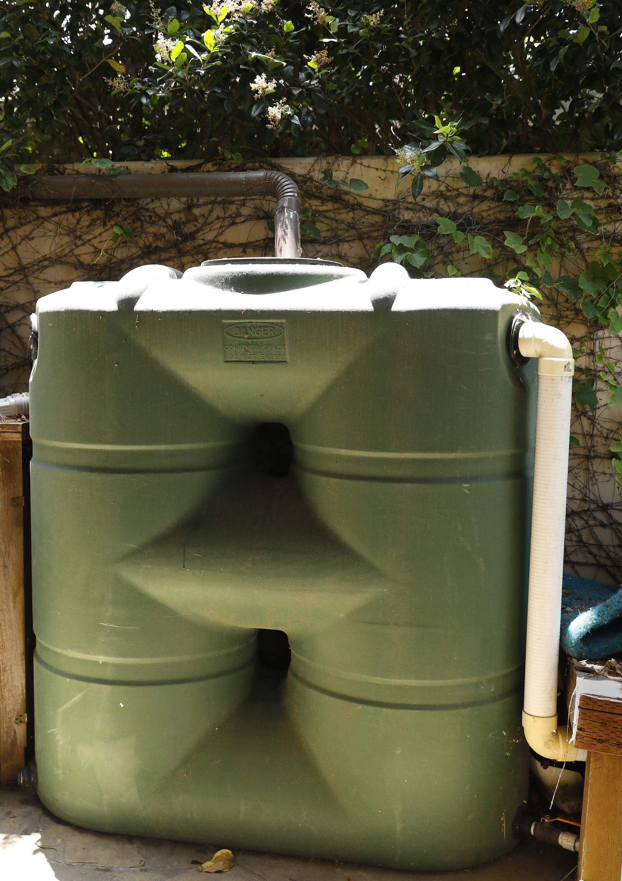 A waffle-shaped aboveground water tank against a backyard fence. 