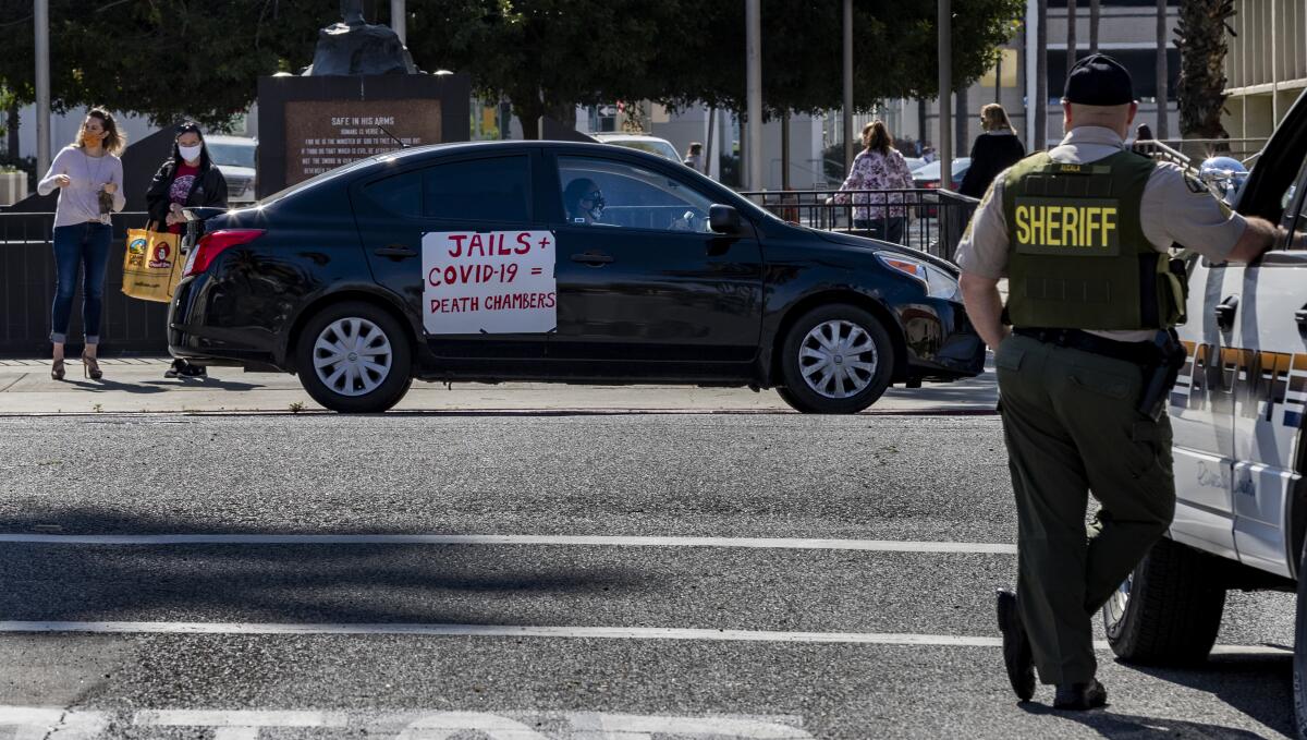 A Riverside County sheriff's deputy keeps watch during a car rally to protest conditions in Riverside County jails, where there has been a coronavirus outbreak.