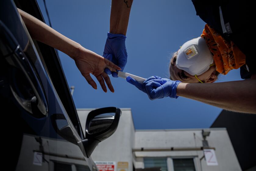 LOS ANGELES, CALIF. -- THURSDAY, MAY 7, 2020: After making a finger prick to draw blood from a patient, Hannah Veal places the blood on the antibody testing device at a drive through testing site in a parking lot behind the Westside Walk-in Clinic in Los Angeles, Calif., on May 7, 2020. (Marcus Yam / Los Angeles Times)