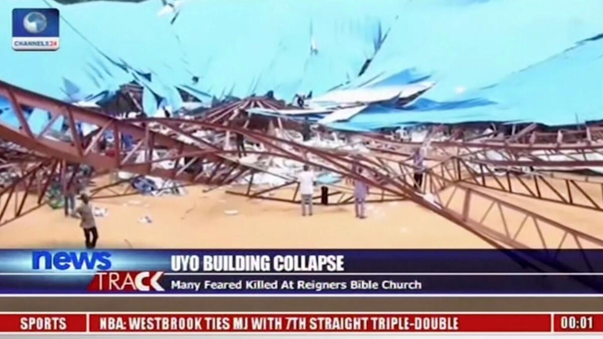 In an image taken from video, people stand at the scene after the roof of the Reigners Bible Church International collapsed onto worshipers in Uyo, Nigeria, on Dec. 10.