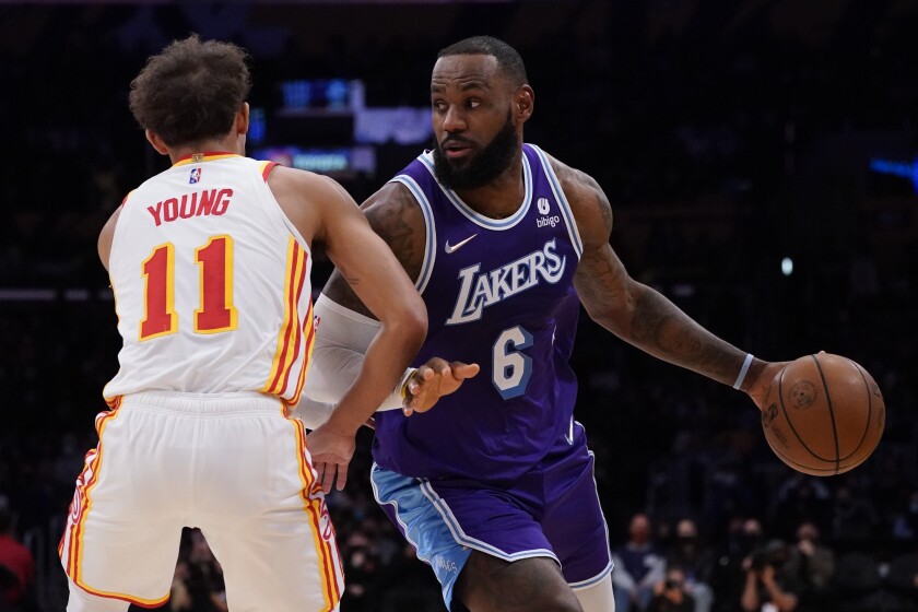 Atlanta Hawks guard Trae Young (11) defends against Los Angeles Lakers forward LeBron James (6) during the first half of an NBA basketball game in Los Angeles, Friday, Jan. 7, 2022. (AP Photo/Ashley Landis)