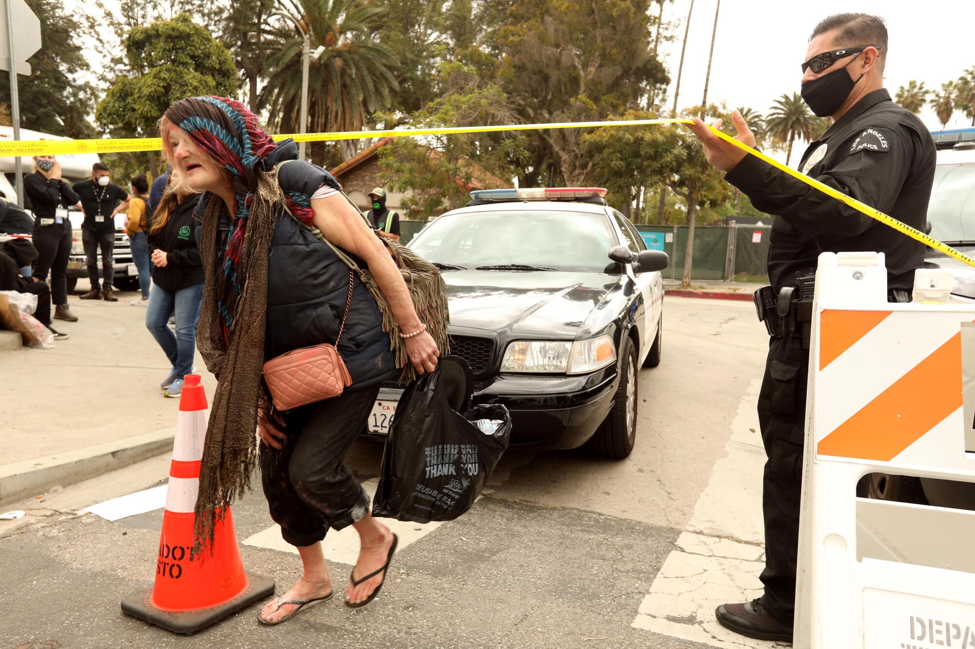  A police officer lifts police tape to let a woman pass. 