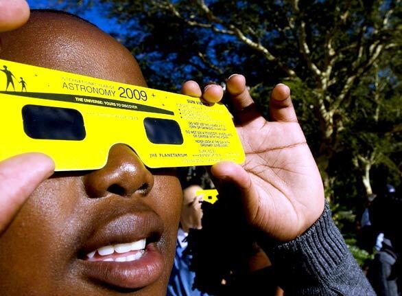 A young boy looks through dark glasses at the Planetarium of the national Museum in Cape Town, South Africa, to view a partial solar eclipse.