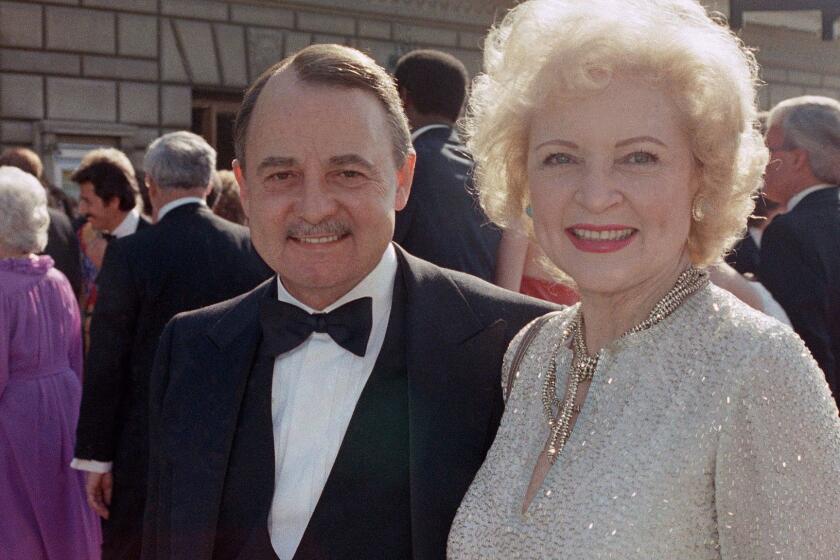 FILE- This Sept. 22, 1985, file photo shows John Hillerman, left, and Betty White, right, arriving at Emmy Awards in Pasadena, Calif. A spokeswoman for the family of Hillerman says the co-star of TVâs âMagnum, P.I.â has died. Hillerman was 84. Spokeswoman Lori De Waal said Hillerman died Thursday at his home in Houston. She said the cause of death has yet to be determined. (AP Photo/LIU, File)