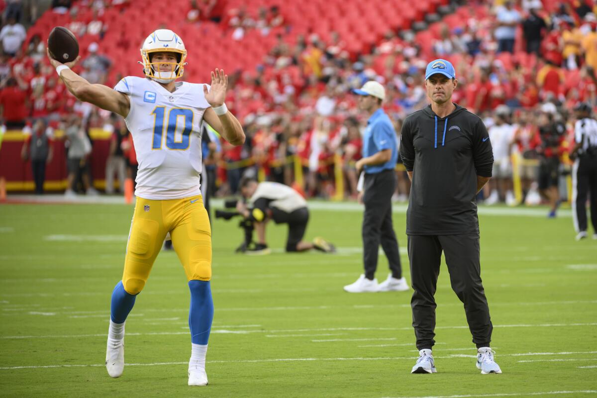 Chargers head coach Brandon Staley watches quarterback Justin Herbert (10) warm up.